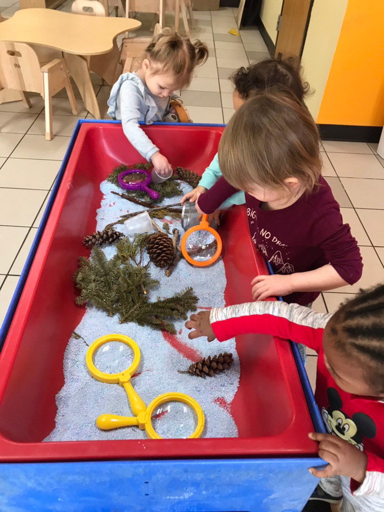 Children exploring sensory table with magnifying glasses